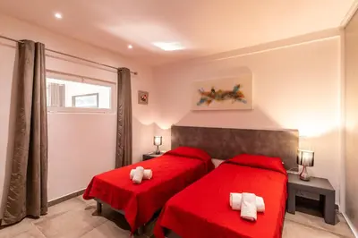 a bedroom with two red beds and a window at Les Arcades de Cala Rossa in Lecci