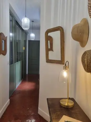a table with a lamp and a mirror on a wall at Appartement CLADA/ Côté Lac in Ajaccio