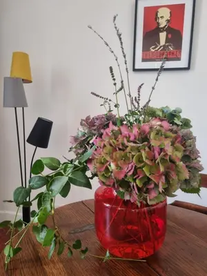 a red vase filled with flowers on a table at Appartement CLADA/ Côté Lac in Ajaccio
