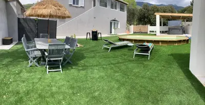 a lawn with chairs and a table and a grill at Les jardins de Funtanone in Vignale