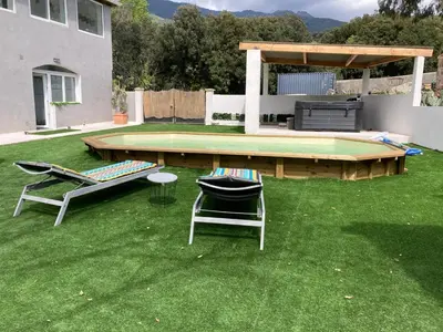 a yard with two chairs and a table and a pool at Les jardins de Funtanone in Vignale