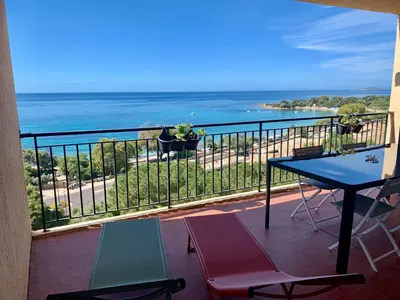 a balcony with a table and chairs and the ocean at Superbe appartement T2 Vue magnifique Sanguinaires à 50m de la plage in Ajaccio