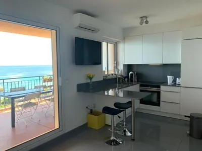 a kitchen with a counter and a view of the ocean at Superbe appartement T2 Vue magnifique Sanguinaires à 50m de la plage in Ajaccio