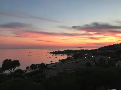 a sunset over a body of water with boats at Superbe appartement T2 Vue magnifique Sanguinaires à 50m de la plage in Ajaccio