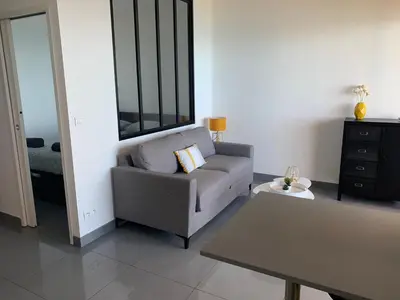 a living room with a chair and a table at Superbe appartement T2 Vue magnifique Sanguinaires à 50m de la plage in Ajaccio