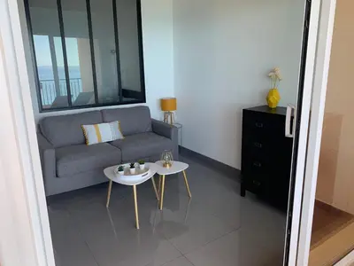 a living room with a couch and a table at Superbe appartement T2 Vue magnifique Sanguinaires à 50m de la plage in Ajaccio