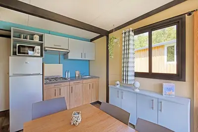 a kitchen with a table and a white refrigerator at Camping l'Oso in Porto-Vecchio