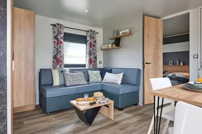 a living room with a blue couch and a table at Camping l'Oso in Porto-Vecchio