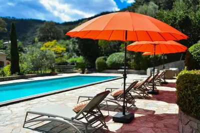 a row of chairs with umbrellas next to a pool at Villa à Conca avec piscine pour 8 personnes en Corse du Sud in Conca