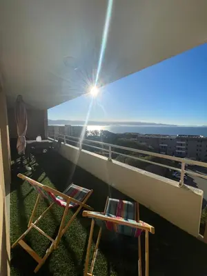 a balcony with two chairs and a view of the ocean at Bagnu di sole - sur la route des îles sanguinaires adorable T2 vue mer in Ajaccio