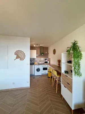 a kitchen with a table and a kitchen with white appliances at Bagnu di sole - sur la route des îles sanguinaires adorable T2 vue mer in Ajaccio
