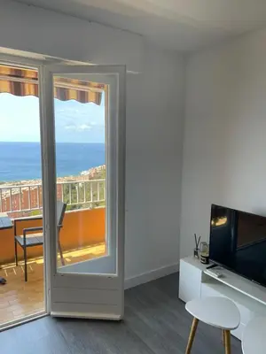a room with a sliding glass door with a view of the ocean at Splendide vue dans ce studio ! in Ajaccio