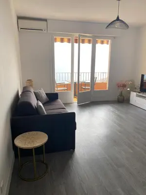 a living room with a blue couch and a table at Splendide vue dans ce studio ! in Ajaccio
