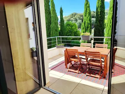 a balcony with a wooden table and chairs on a patio at ARCA C14 in Porto-Vecchio