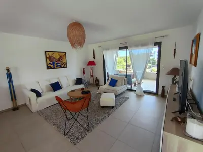 a living room with a white couch and a tv at ARCA C14 in Porto-Vecchio