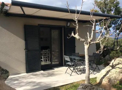 a patio with a table and chairs next to a house at Coquet appartement indépendant entre mer et maquis in Sotta