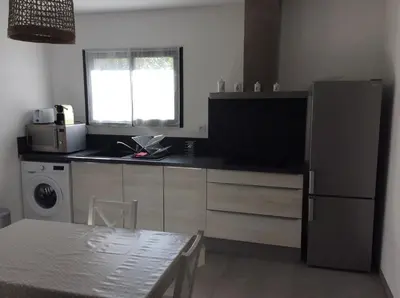 a kitchen with a refrigerator and a table and a window at Coquet appartement indépendant entre mer et maquis in Sotta