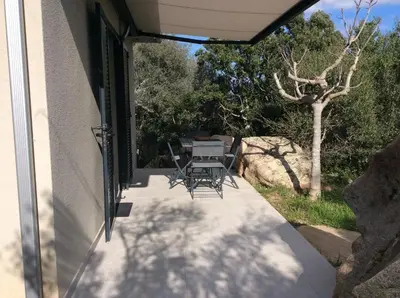 a patio with a table and chairs on the side of a house at Coquet appartement indépendant entre mer et maquis in Sotta