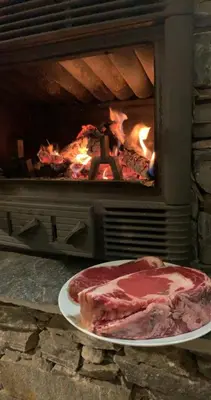 a piece of meat on a plate in front of a fireplace at A Casetta d’Hélène et Jeanette in Omessa