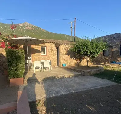 a patio with an umbrella and chairs and a house at Maison Le Prunier avec piscine - Domaine E Case Di Cuttoli in Cuttoli-Corticchiato