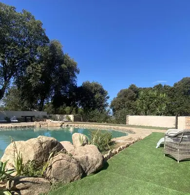 a swimming pool with rocks in a yard at Maison Le Prunier avec piscine - Domaine E Case Di Cuttoli in Cuttoli-Corticchiato