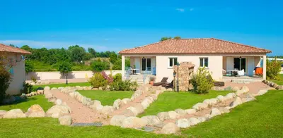 a yard with a stone wall in front of a house at Alzitone in Ghisonaccia