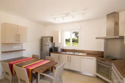 a kitchen with a wooden table and a table and chairs at Alzitone in Ghisonaccia