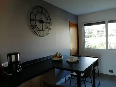 a kitchen with a table and a clock on the wall at Centre ville avec vue magnifique sur le golfe d'Ajaccio; parking privé. in Ajaccio