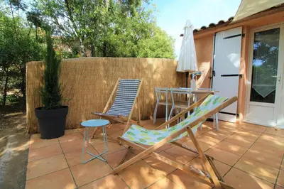 a patio with chairs and a table and an umbrella at Rogliano in Porto-Vecchio