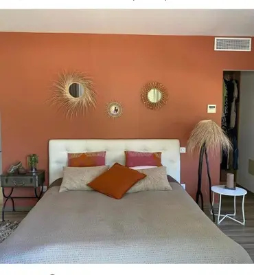 a bedroom with an orange wall with a bed and two mirrors at Chambre à Louer sur bonifacio in Bonifacio