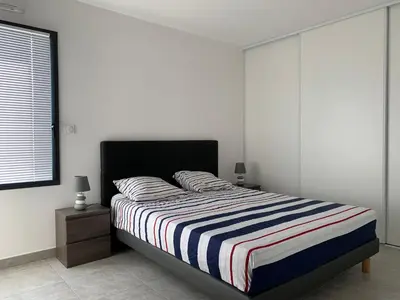 a bedroom with a bed with a striped blanket at Appartement T3 de standing, vue mer - Porticcio in Grosseto-Prugna