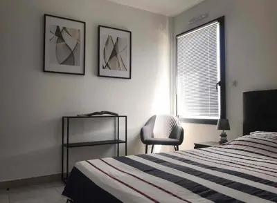a bedroom with a bed and a chair and a window at Appartement T3 de standing, vue mer - Porticcio in Grosseto-Prugna