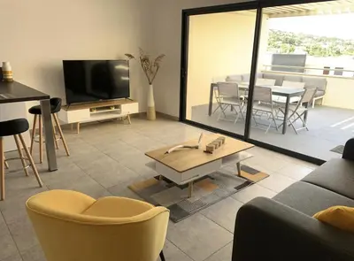 a living room with a couch and a tv and a table at Appartement T3 de standing, vue mer - Porticcio in Grosseto-Prugna