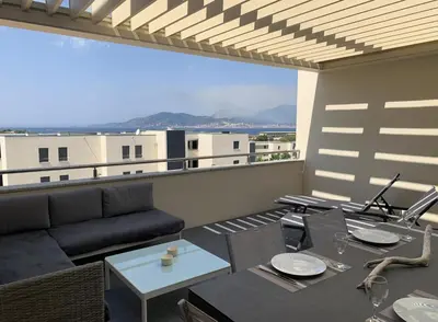 a living room with a couch and a table on a balcony at Appartement T3 de standing, vue mer - Porticcio in Grosseto-Prugna