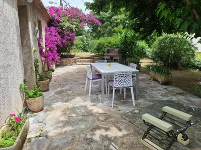 a patio with a table and chairs and flowers at maisonnette à la campagne in San-Gavino-di-Carbini