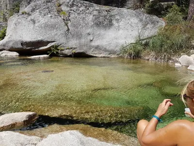 a woman sitting in a pool of water next to a river at maisonnette à la campagne in San-Gavino-di-Carbini