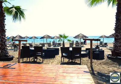 a sandy beach with tables and chairs and umbrellas at apartment on the sea - Moriani beach in San-Nicolao