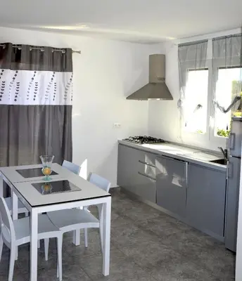 a kitchen with red cabinets and a counter with stools at T-2 air conditioning close to the sea - equipped beach - Santa Lucia di Moriani in San-Nicolao