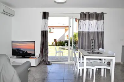 a living room with a dining table and a television at T-2 air conditioning close to the sea - equipped beach - Santa Lucia di Moriani in San-Nicolao