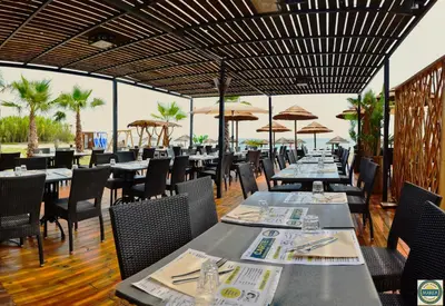 a dining room with tables and chairs and umbrellas at Apartment next to the sea 4 peoples-WIFI-TV-Air Conditioning-Moriani Haute-Corse in San-Nicolao