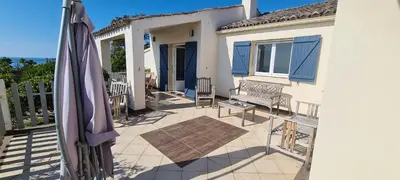 a patio with an umbrella and a bench on a balcony at Belvedere de Canaloro in Sari Solenzara