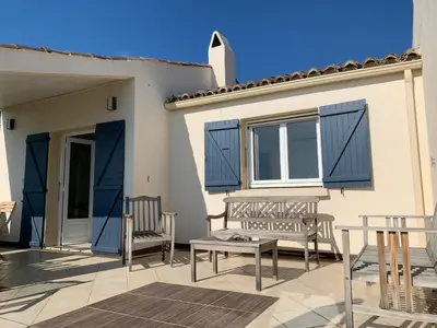 a patio with two benches and a house with blue shutters at Belvedere de Canaloro in Sari Solenzara