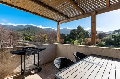 a table and chairs on a balcony with a view of mountains at Le Clos d'Oletta in Oletta