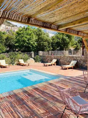 a patio with a swimming pool with chairs and a table at Villa de standing, piscine chauffée,Balagne, Pietralba in Pietralba