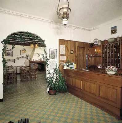 a restaurant with a counter and a dining room at Hôtel Aïtone in Evisa