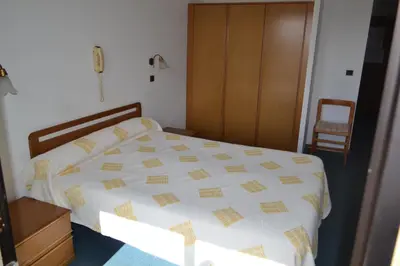a bedroom with a bed with a white and yellow comforter at Hôtel Aïtone in Evisa