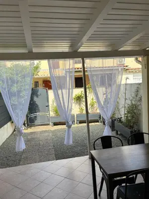a patio with white curtains and a table and chairs at Mini villa chaleureuse avec vue mer imprenable in San-Nicolao