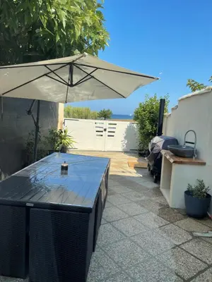 a table with an umbrella on a patio at Mini villa chaleureuse avec vue mer imprenable in San-Nicolao