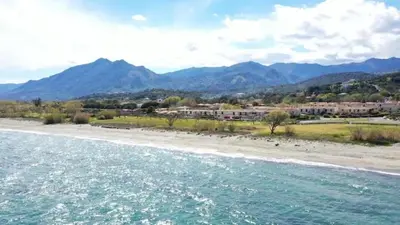 a view of a beach with mountains in the background at Mini villa chaleureuse avec vue mer imprenable in San-Nicolao