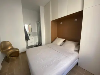 a small bedroom with a white bed and a chair at 2 pièces / neuf - Ajaccio centre - Place Miot / Albert 1er in Ajaccio